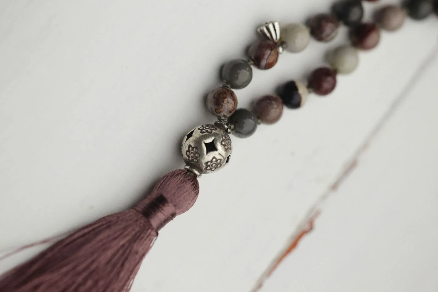 Natural-toned beads with a woven tassel on a pale surface